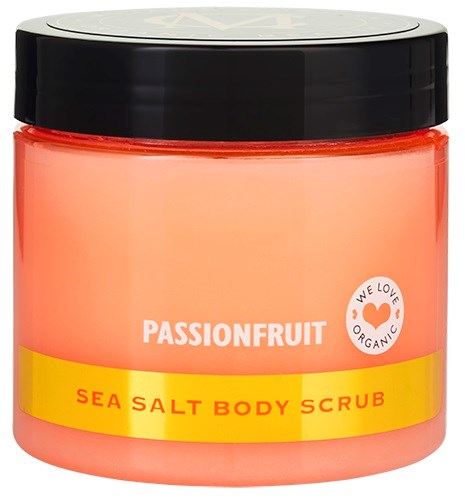Ett persikatonat glas med Passionfruit Sea Salt Body Scrub, svart lock och en etikett som säger "We Love Organic."
