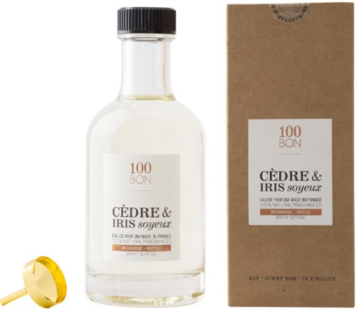 En parfyllflaska och ett boxmärke som heter 'Cèdre & Iris Soyeux' med en guldfärgad kork.