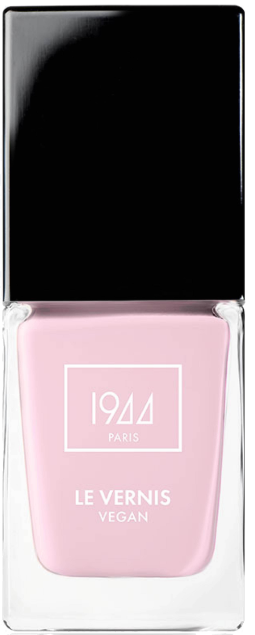 En rosa nagellackflaska med svart lock, märkt '1944 PARIS LE VERNIS VEGAN' i ett klart hölje.