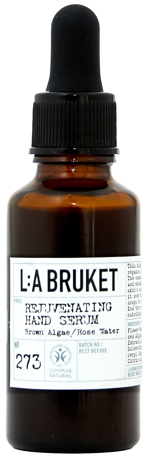 Eine braune Flasche mit schwarzem Tropfenzwing, beschriftet 'L:A BRUKET Rejuvenating Hand Serum' mit natürlichen Inhaltsstoffen.