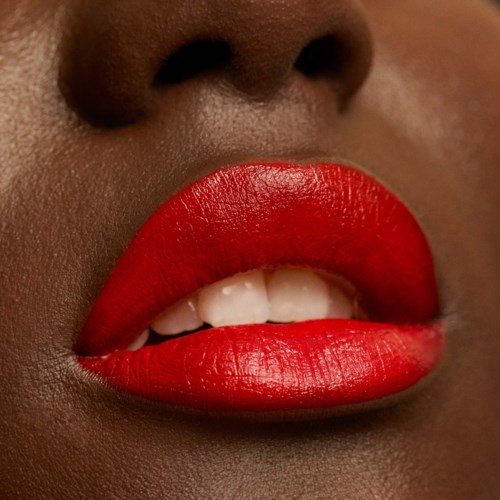 Close-up of lips with bright red lipstick and slightly parted teeth, skin tone visible around lips.