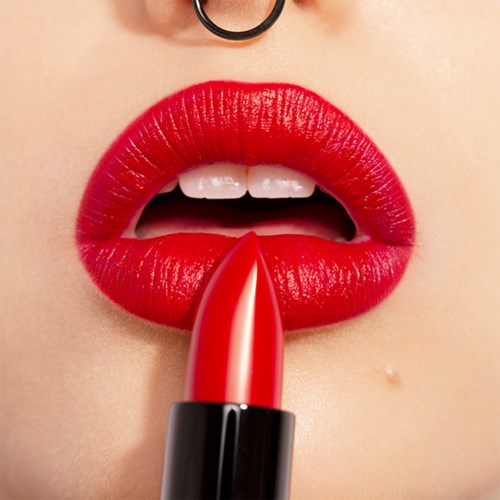 Close-up of red lipstick on lips, with teeth partially visible. A small nose ring is also seen.