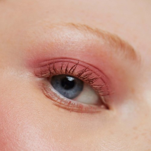 Close-up of a person's eye with makeup, showing blue color and long eyelashes.