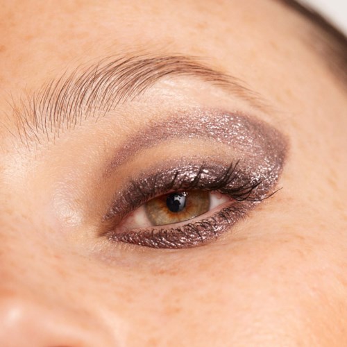 Close-up of a finished eye makeup with glitter eyeshadow, eyeliner, and long eyelashes.