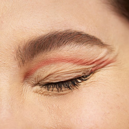A close-up of a person's closed eye showing eyebrows, eyelid, and eyelashes with detailed skin texture.