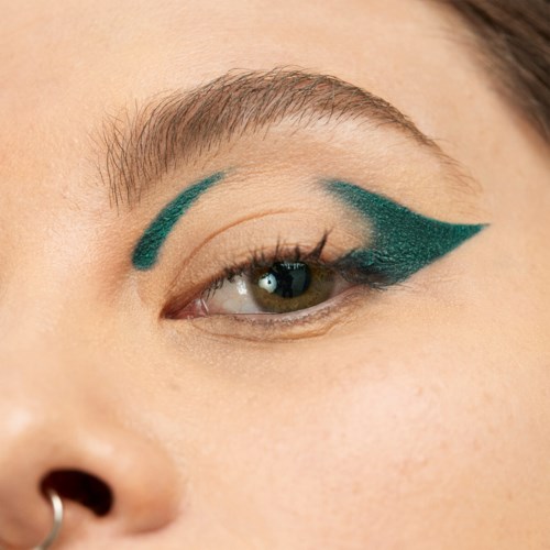 Close-up of a woman's face showing bold teal eye makeup and neatly groomed eyebrows.