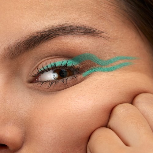 Close-up of a woman's eye with teal eye makeup and two wavy lines drawn near the eye.