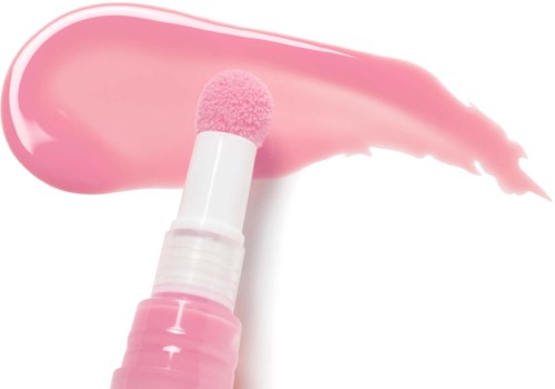 Ein rosa Applikator mit rosa Creme oder Lotion auf weißem Hintergrund.