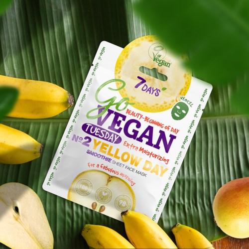 Vegan ansiktsmaske emballasje på grønne bananblader omgitt av bananer og fersken.