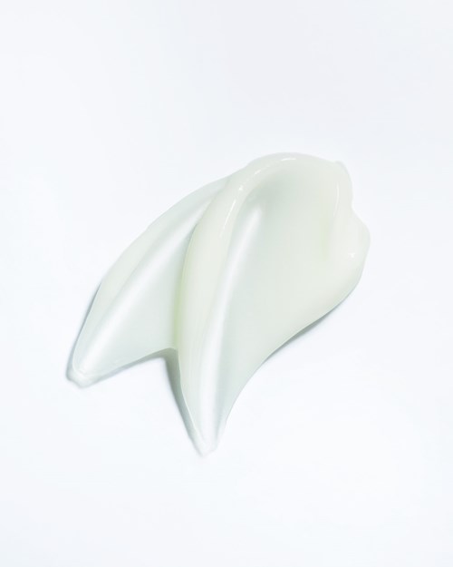 Een hoopje witte crème of lotion op een witte achtergrond.