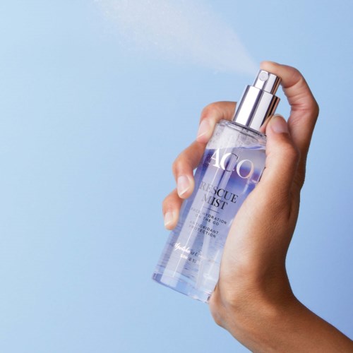 A hand sprays clear liquid from a bottle labeled 'Rescue Mist' onto a blue background.