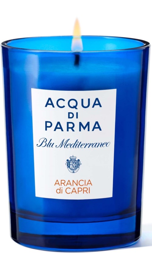 Blue candle in a glass holder with a lit wick. Label says 'Acqua di Parma' and 'Arancia di Capri.'
