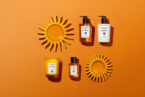 Skincare products arranged on an orange background with sun-shaped decor pieces, labeled Acqua di Parma. Simple and bright.