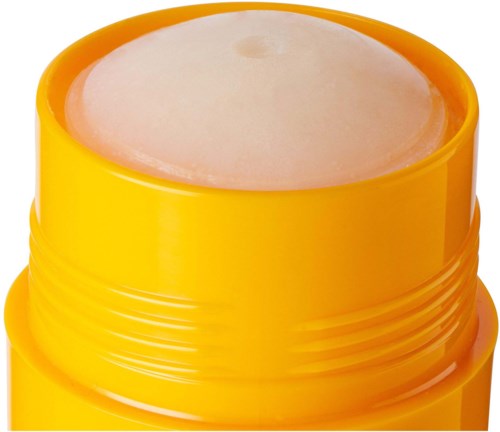 En gul behållare med ett vitt, fast läppbalsam eller kosmetikaprodukt inuti.