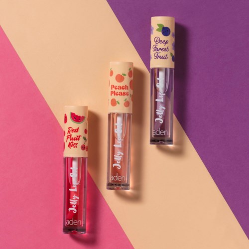 Three lip balm tubes with fruit illustrations and names, placed on a pink, beige, and purple background.