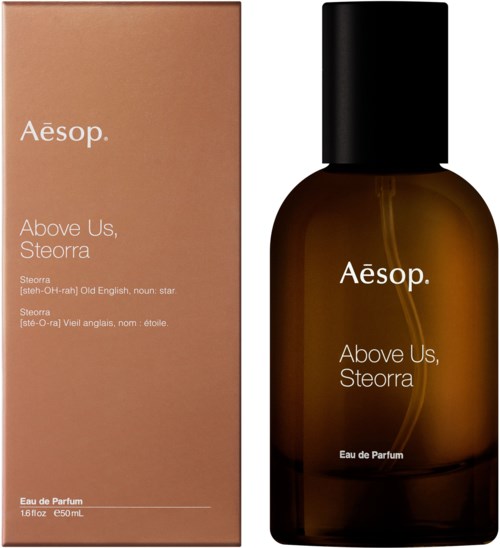 Een parfumfles en doos met de naam Aesop Above Us, Steorra, met eenvoudige tekst, bruin en zwart.