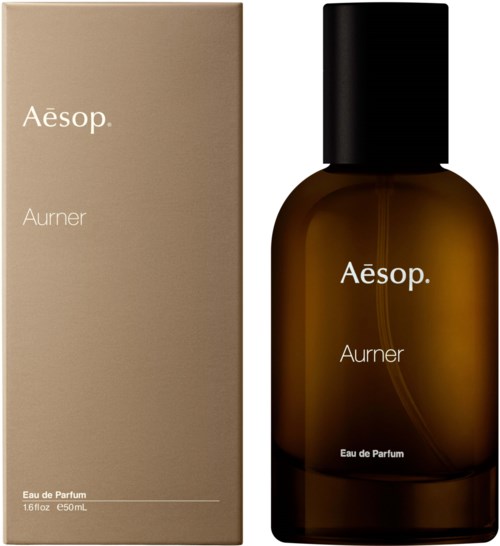 En brun parfygbarre med sort låg og en beige æske, begge mærket 'Aesop Aurier Eau de Parfum'.
