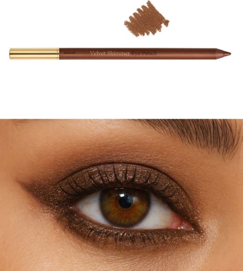 Brązowe oko z złotym cieniem do powiek, eyelinerem i tuszem. Nad nim jest brązowa kredka do oczu oznaczona jako 'Velvet Shimmer Eye Pencil'.