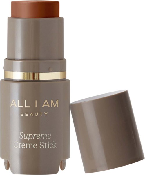 En grå cylindrical behållare med guld- och vit_text, märkt "ALL I AM BEAUTY Supreme Creme Stick," utan lock.