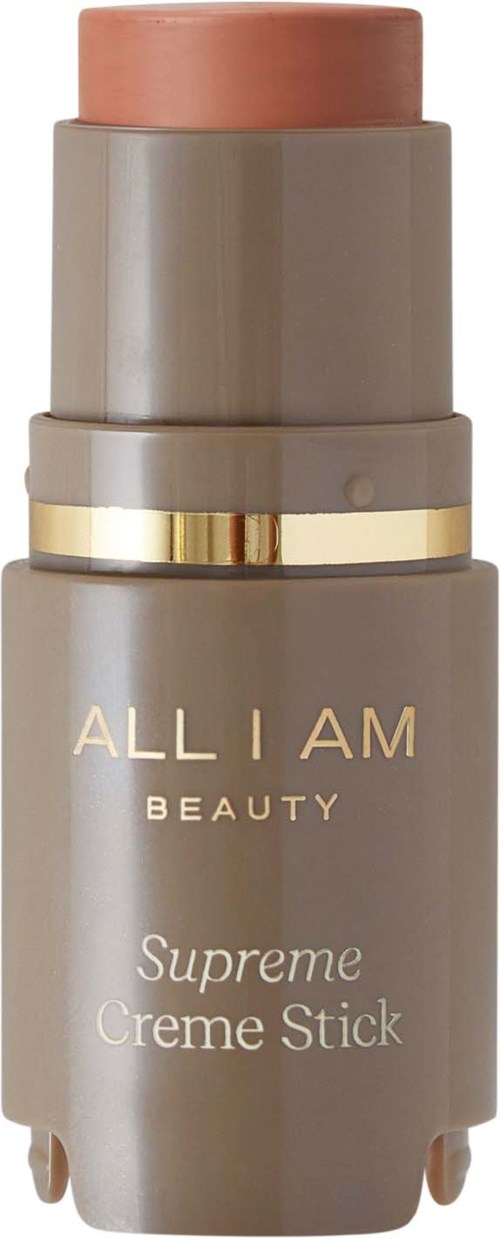 En beige flaska med rosa topp och guldband, märkt 'ALL I AM BEAUTY Supreme Creme Stick'.