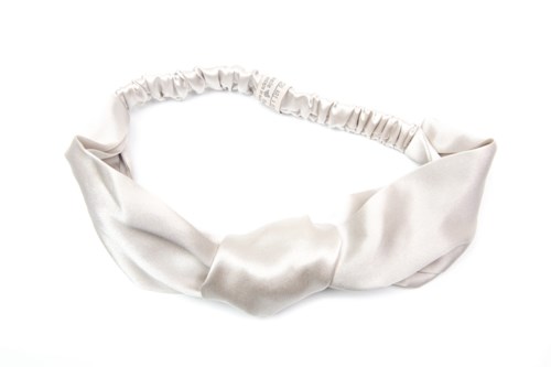 Ett vitt satinhårband med knut och elastisk band för att bära.
