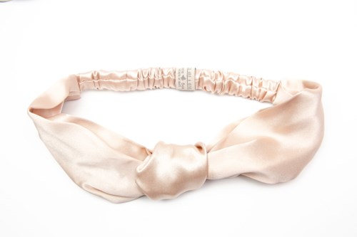 En mjuk rosa satinhårband med en knut framtill. Den ser slät och glänsande ut.