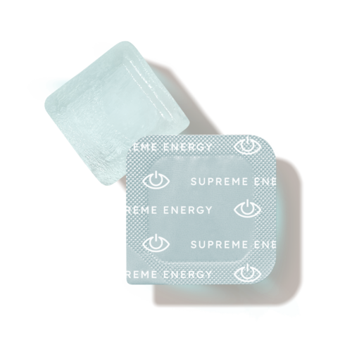 Biały sześcienny przedmiot z małymi niebieskimi uszami i dwoma blisterami tabletek oznaczonymi "Supreme Energy."