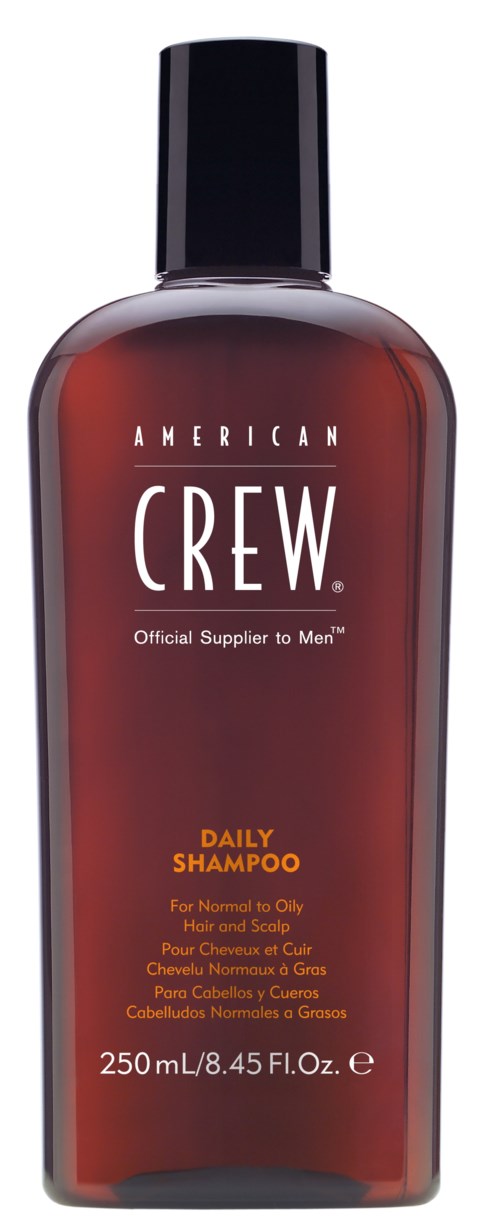 En brun flaska med svart lock, märkt American Crew Daily Shampoo för normalt till fett hår.