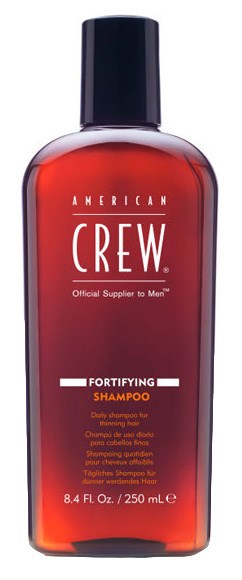 Röd schampoflaska med svart lock, märkt 'American Crew Fortifying Shampoo'.