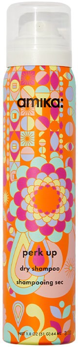 A tall, colorful bottle with a white cap, decorated with bright, floral and geometric patterns. It is a dry shampoo.