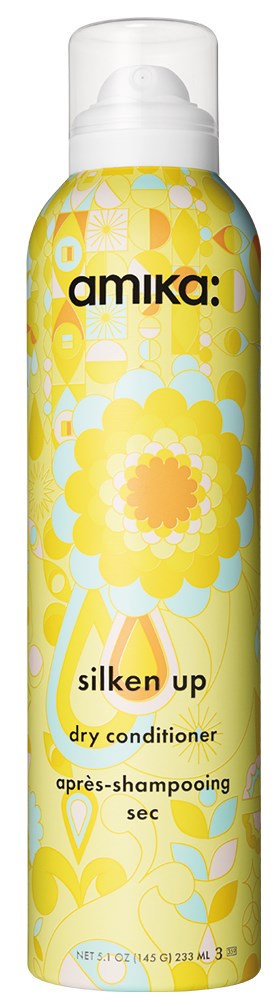 En gul flaska med blommönster, märkt 'amika: silken up dry conditioner', och en vit topp.