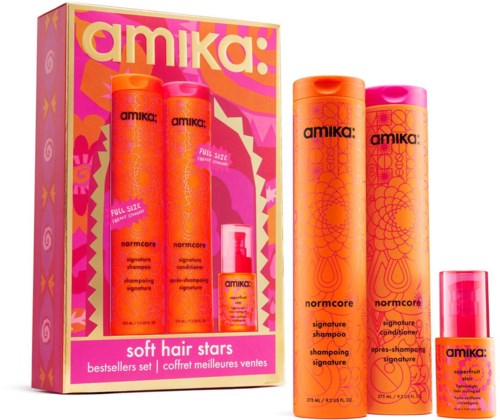 Sæt med Amika normcore signature shampoo, balsam og en lille hårplejeprodukt i pink og orange flasker med lyst emballage.