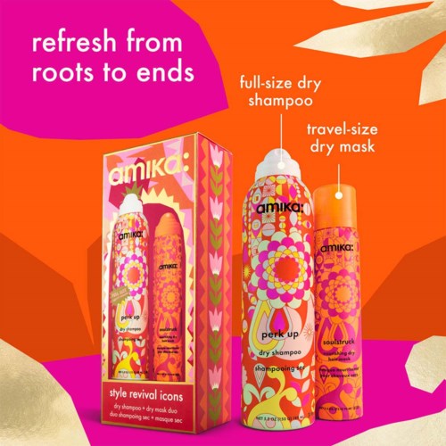Verpackung der Amika Trockenshampooflaschen mit buntem Blumen- und Geometriedesign vor leuchtend orange-rosa Hintergrund.