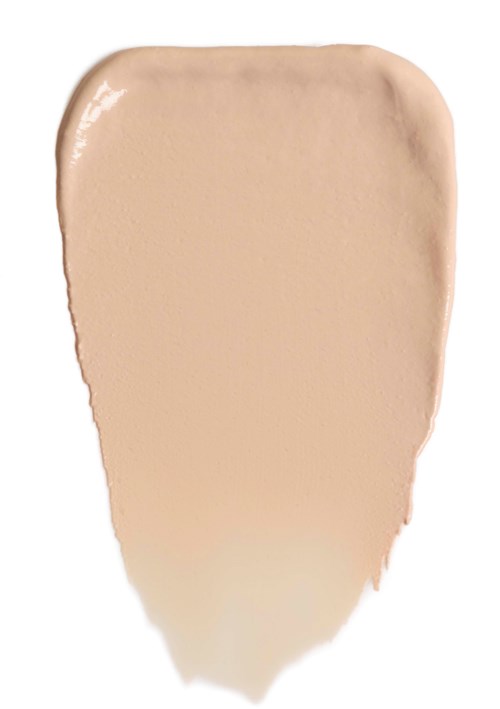 En beige sminkeprøve med avrundet øvre del og smalere nederdel. Den ser jevn og kremaktig ut.