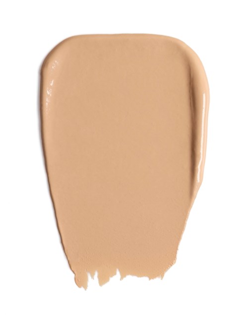 En beige flytende foundationprøve på hvit bakgrunn.