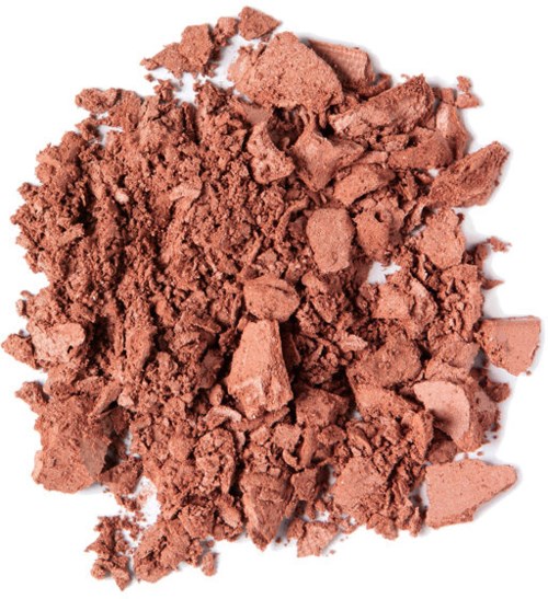 Opløst makeupprodukt med lyserødbrun farve og pulveragtig tekstur.