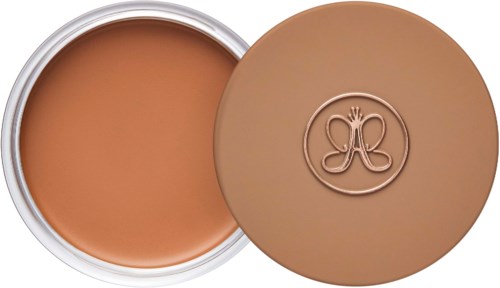 A round container with light brown cream or foundation, and a matching lid with a logo.