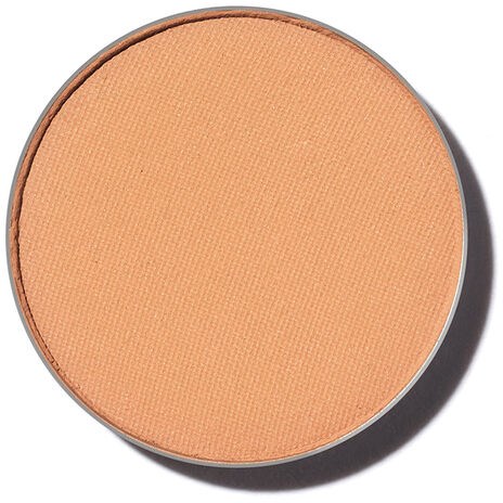 En rund, persikfärgad makeup-blush eller pressad puder i ett kompakt.
