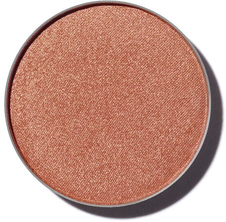 En rund makeuprouge eller ögonskugga i en persikofärgad, skimrig nyans med en texturerad yta.
