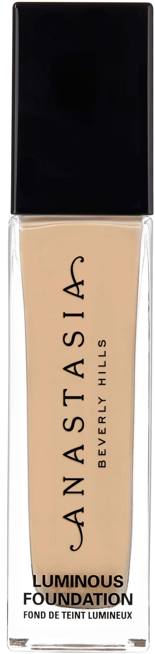 En lång flaska med beige flytande foundation med svart lock och etikett, märkt Anastasia Beverly Hills, Luminous Foundation.