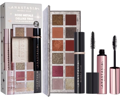 Sminkset med ögonskuggor, mascara och highlighter, placerade i en box och på en vit bakgrund.