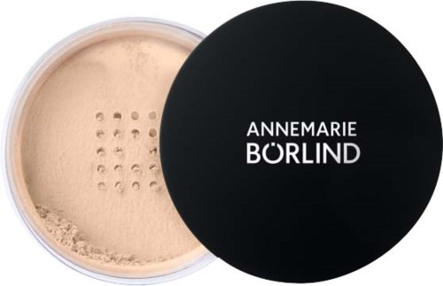En rund beholder med beige pulver og svart lokk med hvit tekst som sier 'ANNEMARIE BORLIND.'