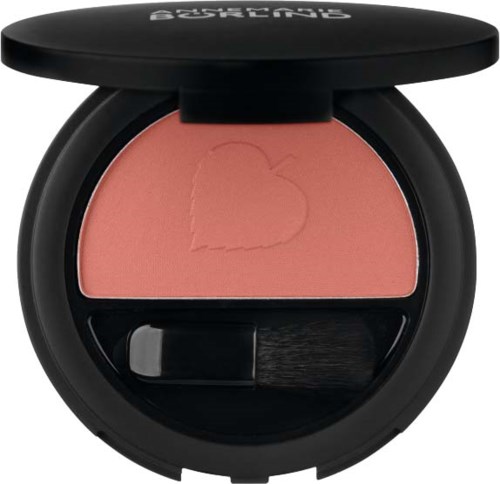 A round compact with peach-colored blush, a heart shape carved into it, and a small brush inside.