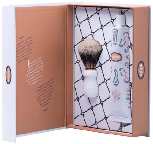 Een scheerset met borstel en crème, in een doos met oranje en witte kleuren, en patronenpapier binnen.