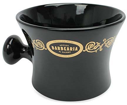 Zwarte keramieken beker met gouden details en een handvat, gelabeld 'Antiga Barbearia do Bairro'.