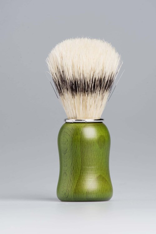 Een scheerkwast met een groene handgreep en witte haren, tegen een eenvoudige achtergrond.