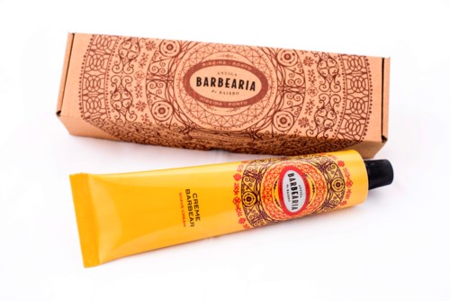 De afbeelding toont een tube baardcrème en een decoratieve kartonnen doos met gedetailleerde patronen.