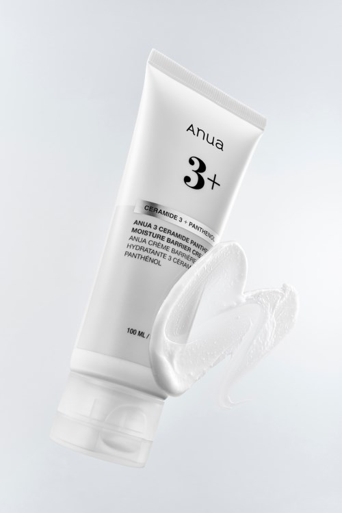 A white tube of skin cream with some cream spilled next to it, on a plain background.