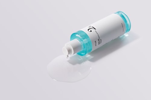 En hvid creme eller lotion er spildt ud af et lille rør med blå låg på en hvid overflade.