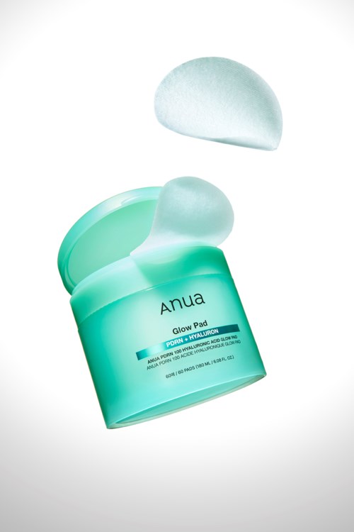 Green container with a lid, labeled 'Anua Glow Pad', open with a white pad above it.